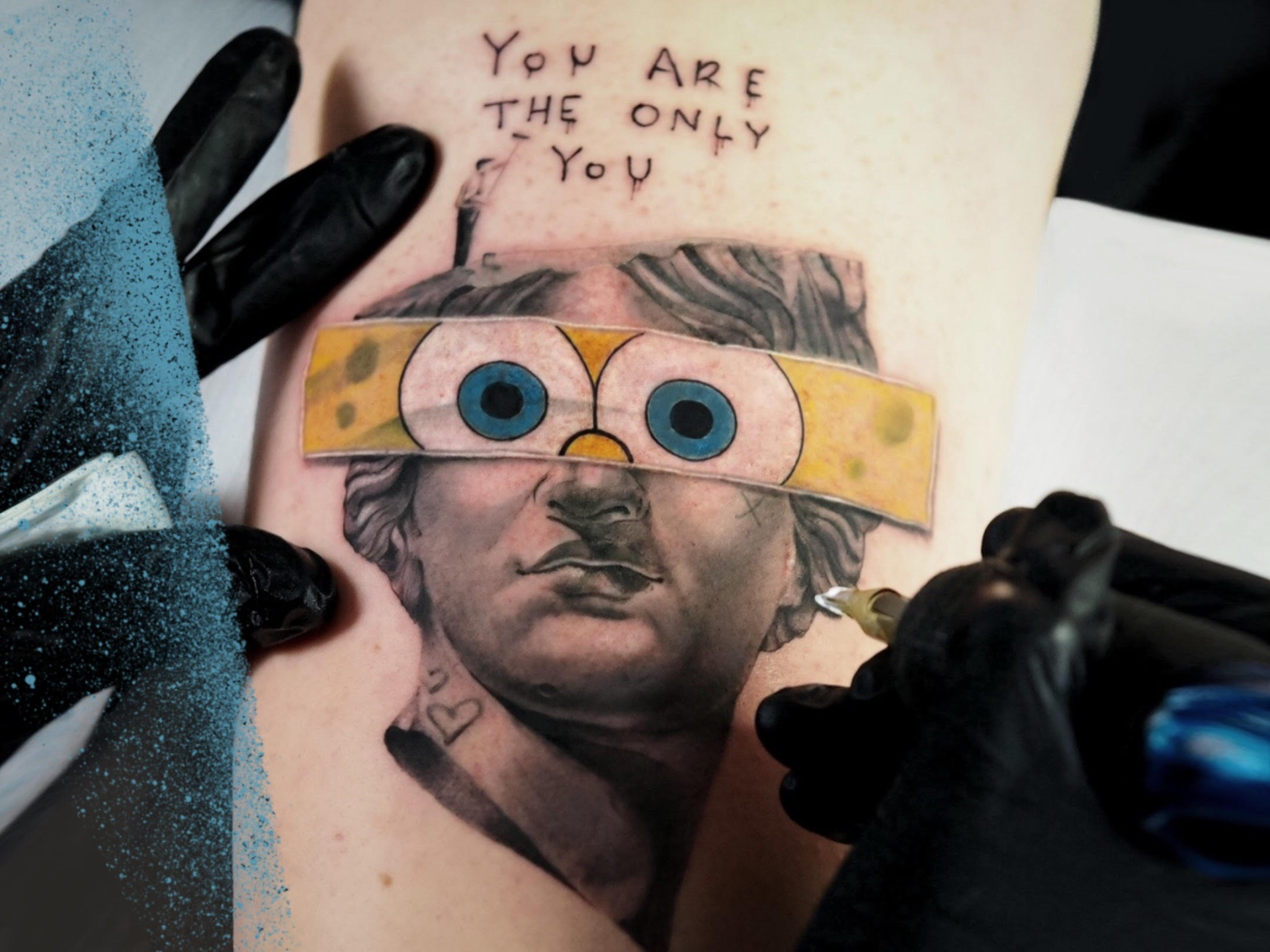 Tatuaż realistyczny przedstawiający twarz greckiej rzeźby z opaską Sponge Bob
